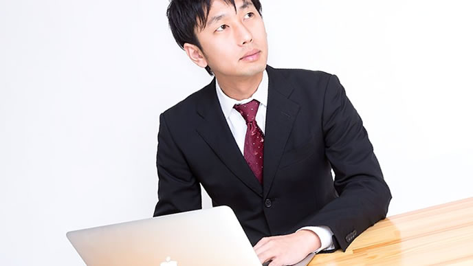 パソコンと手書きで悩む男性