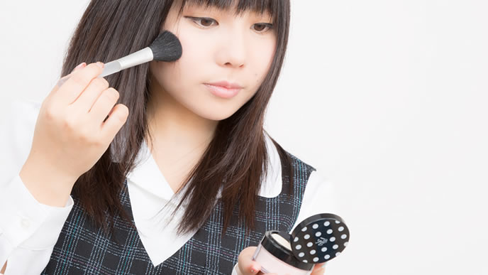 仕事中にベースメイクをする女性