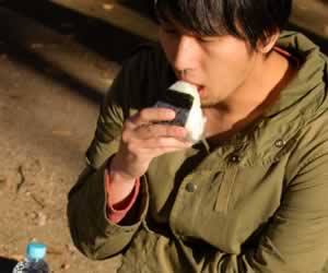 コンビニで買った昼食を食べる男性