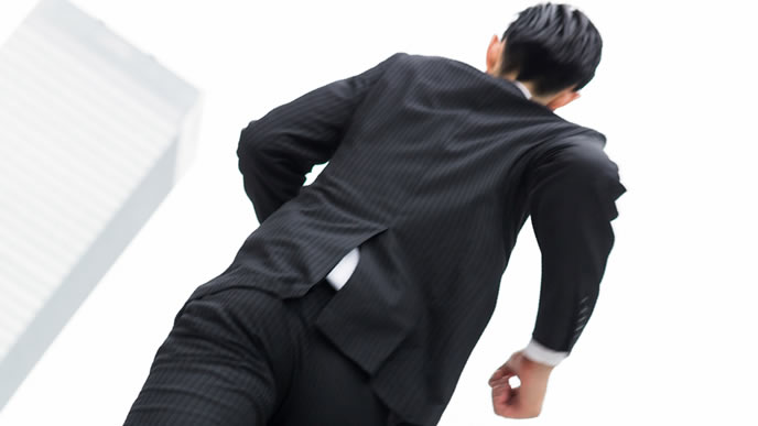 スーツでビルの隙間を走る男性