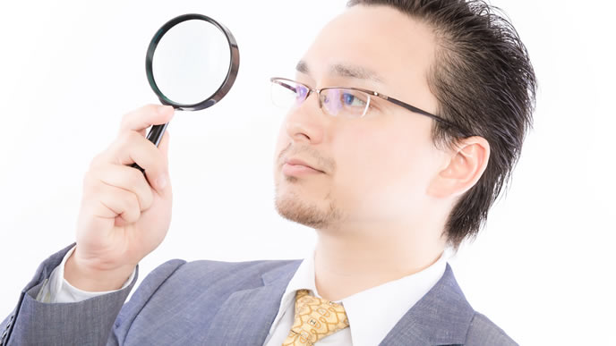 虫眼鏡で今後のビジョンを見る男性