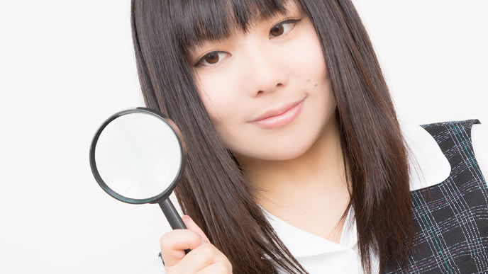 虫めがねでポイントを注視している女性
