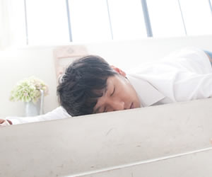 仕事で疲れて倒れこむ男性