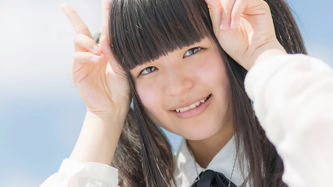 ダブルピースで笑顔を振りまく女性