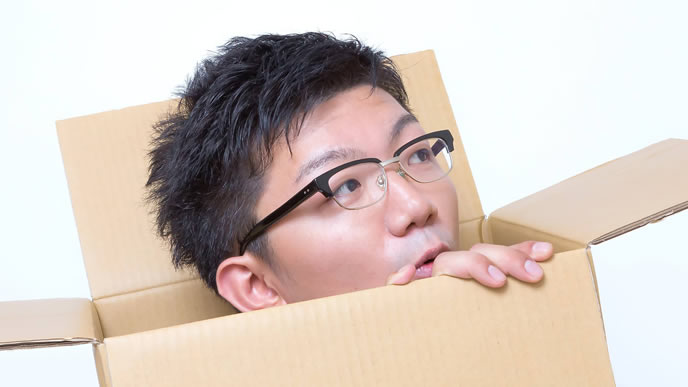 ダンボールから顔を出す男性