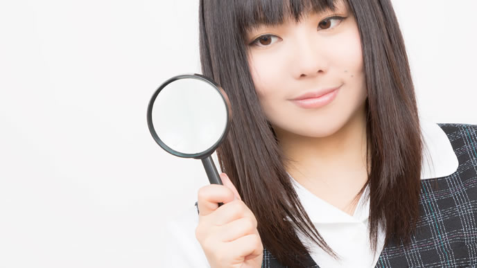 虫眼鏡で新しい情報を発見した女性