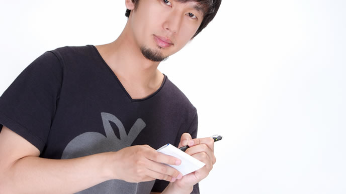 カメラ目線でメモを取る色黒の男性