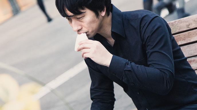 サンドイッチをかじる夜勤明けの男性
