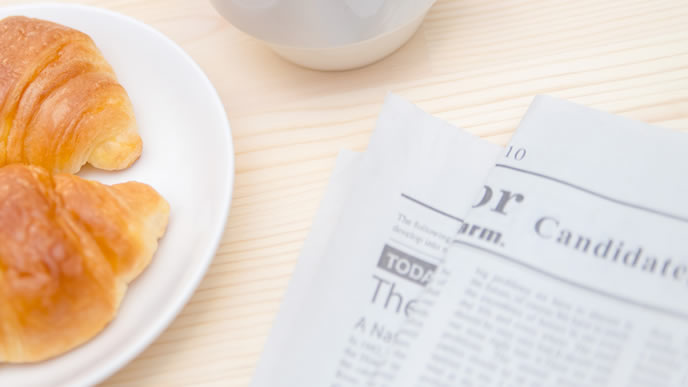 英字の新聞と朝食のクロワッサン