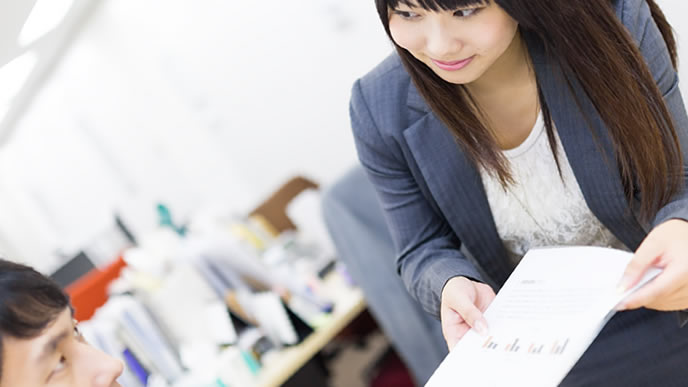 先輩社員に侘びの書類を渡す部下