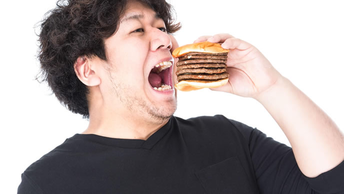 肉が多いハンバーガーを食べる男性