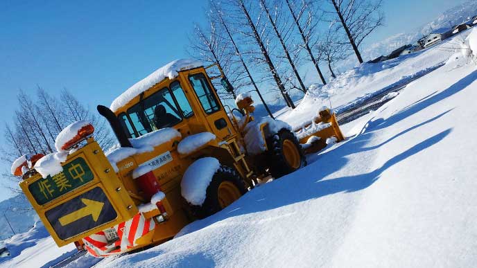 重機を使って除雪をしている季節労働者