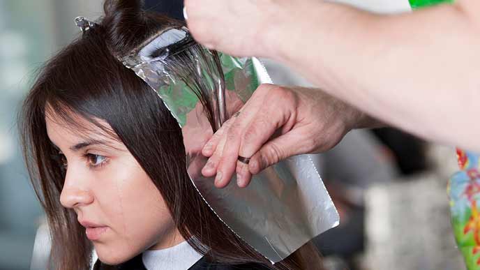 美容院で髪を染める女性