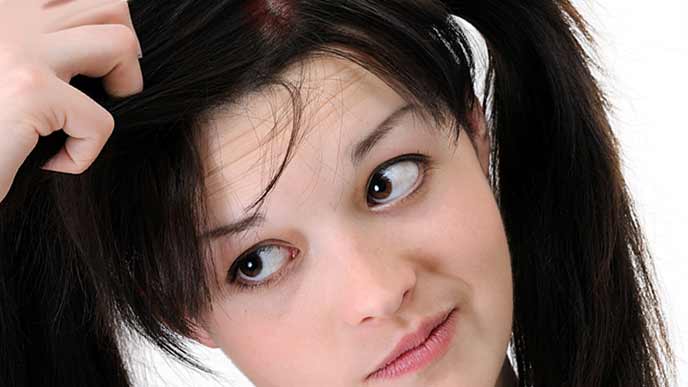 髪の毛の生え際を見つめる女性