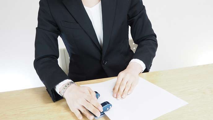 書類にパンチングで穴をあける女性