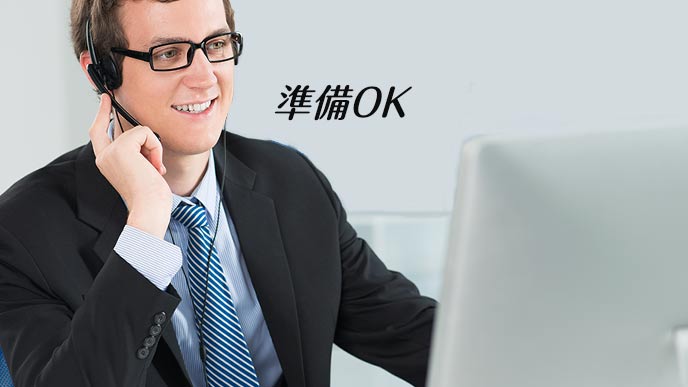 パソコンの前で背広を着てインカムを着ける男性