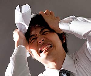 不採用の書類を持って頭を抱える男性