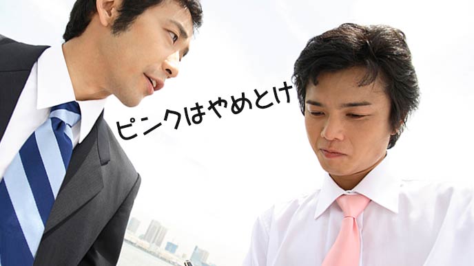 ピンクのネクタイした男性に先輩が忠告する