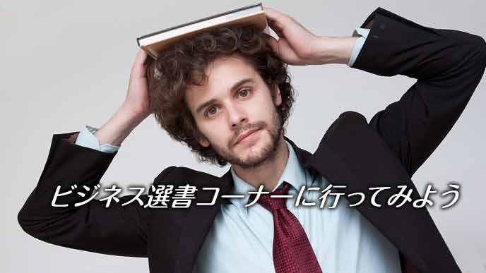 本を頭に載せたビジネスマン