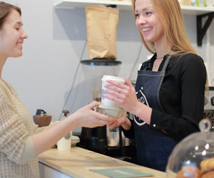 コーヒーを手渡す女性販売員