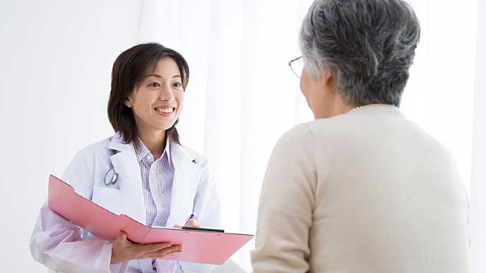 患者の老人を診察する保健師