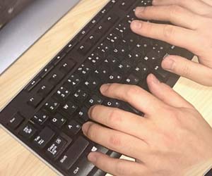 パソコンのキーボードを叩く男性の手