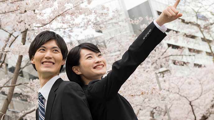 桜の下に立つ新卒学生