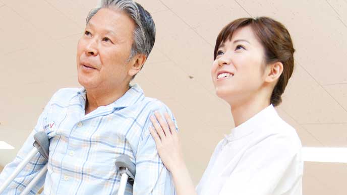 老人の肩を支えてる介護施設で働く行政保健師