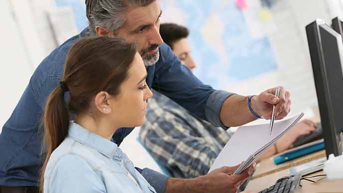 　ベンチャー企業でパソコンをする女子学生と指導する社員