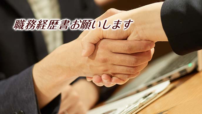 取引先と握手しながら経歴書に言及される