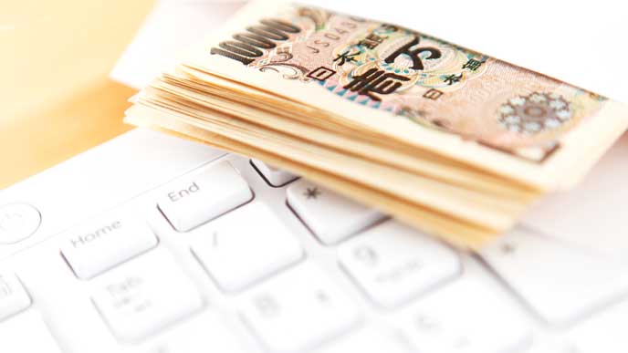 パソコンのキーボードと一万円札が入った封筒