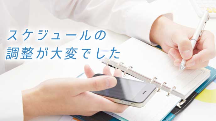 スマホを見ながら手帳にスケジュールをつけるサラリーマン