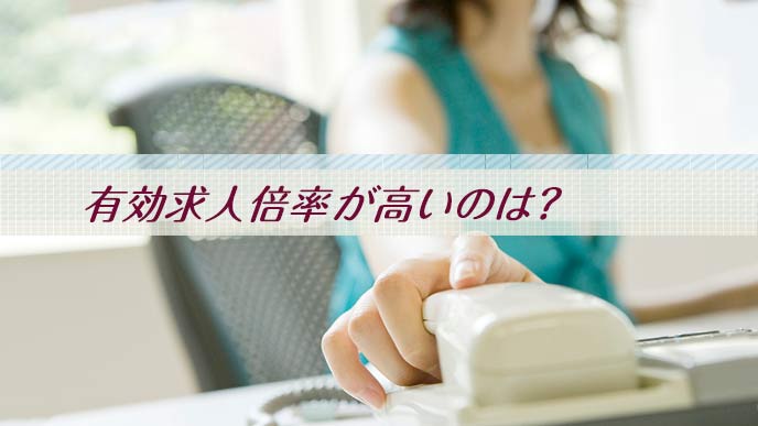 電話に手を伸ばす事務職の女性