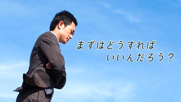 青空を背景に悩んでいるサラリーマン