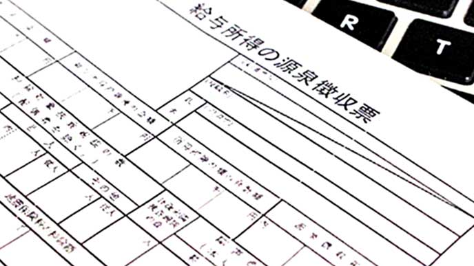 キーボードの上に置かれた源泉徴収票