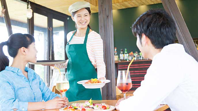 お客様のテーブルに料理を運ぶレストランの店員