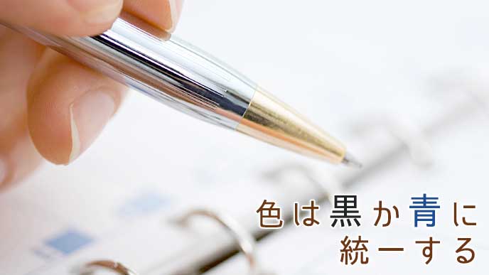 ボールペンを持った手と手帳のページ