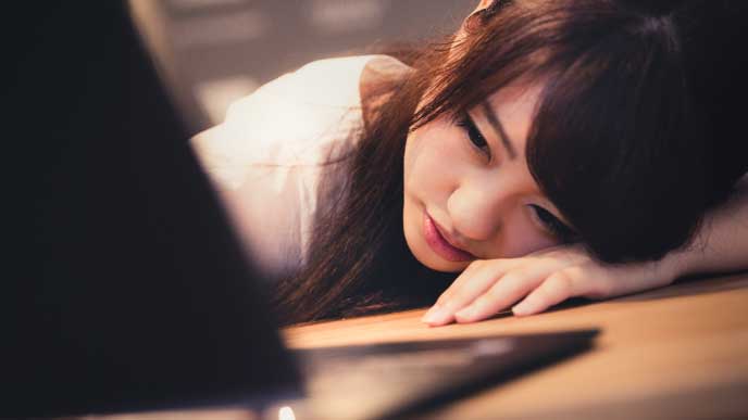 残業で疲れてデスクに倒れかかる会社員の女性
