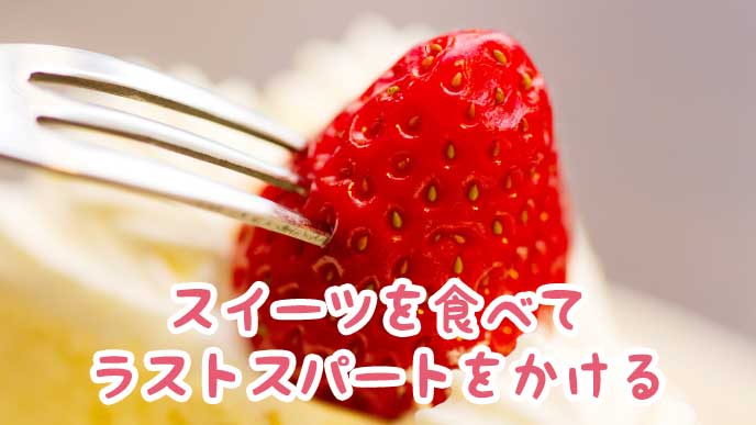ケーキに乗っかった苺にフォークを刺す