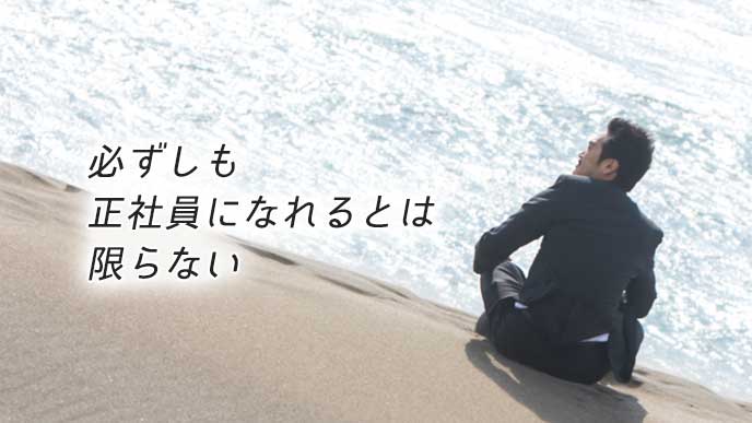 砂浜に座り海を眺める契約社員