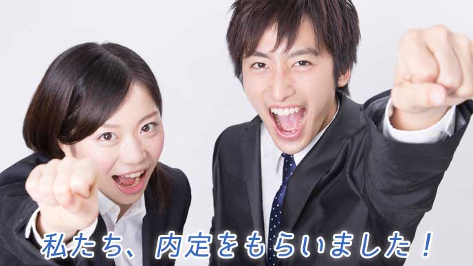 ガッツポーズをとる就活生の男女