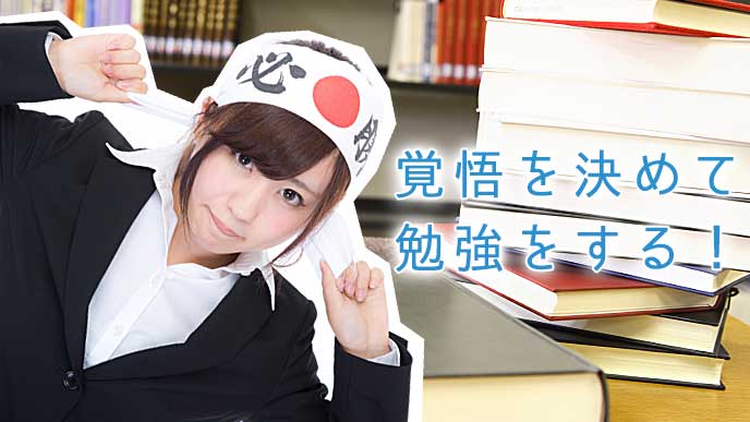 積みあがった本と「必勝」と書かれたハチマキを締めて気合を入れる女性