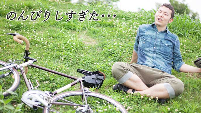 自転車を倒して野原で休息を取っている男