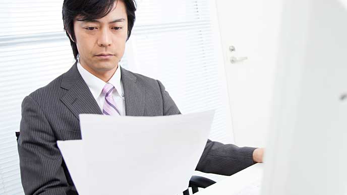 険しい表情でエントリーシートを見ている採用担当者の男性