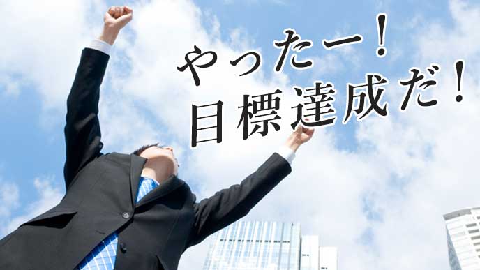 空に向かってガッツポーズを取るビジネスマン