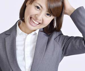 頭に手をやりながら照れ笑いする女性