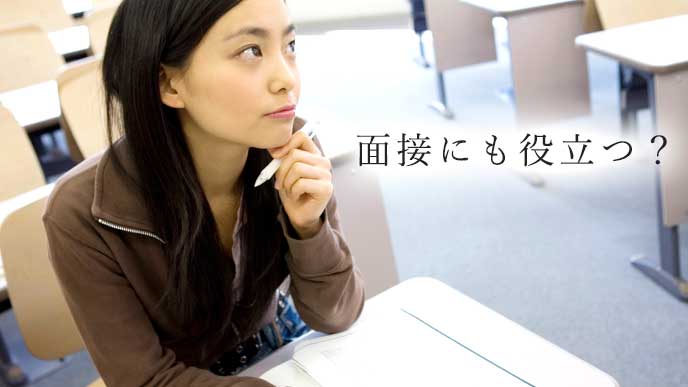 ペンを持って考えている女子大生