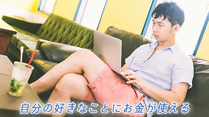 ソファに座りながらノートパソコンを使っている男性