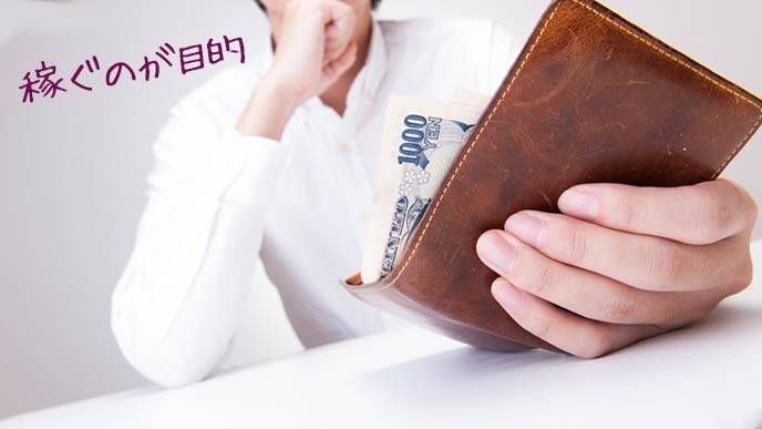 男性が持つ財布から千円札がはみ出る