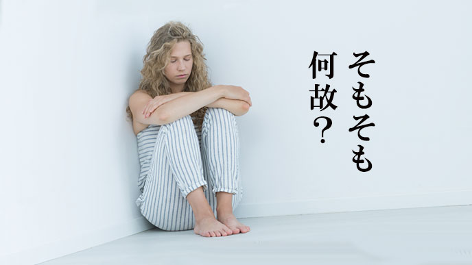 部屋の隅で考え込む女性